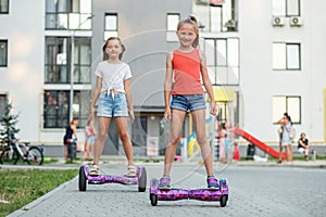 Happy children riding on hoverboards or gyro scooters outdoors in summer. Active life concept