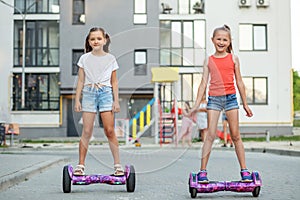 Happy children riding on hoverboards or gyro scooters outdoors in summer. Active life concept