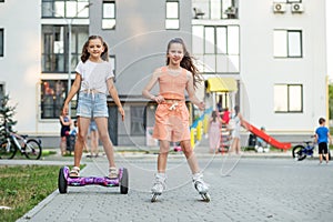 Happy children riding on hoverboards or gyro scooters outdoors in summer. Roller skating