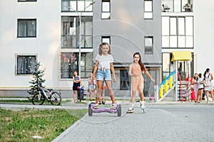 Happy children riding on hoverboards or gyro scooters outdoors in summer. Roller skating