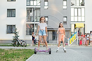 Happy children riding on hoverboards or gyro scooters outdoors in summer. Roller skating