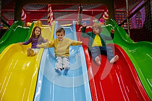Happy children riding slide together at indoor play center