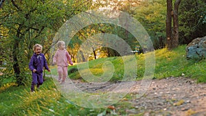 Happy children run together in summer park, two little sisters playing catch-up