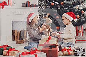 Happy children in santa hats unwrapping christmas presents