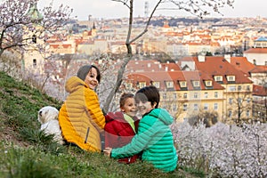 Happy children, siblings, boys, visiting Prague springtime in the evening, walking in park with pet dog
