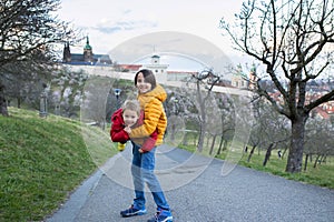 Happy children, siblings, boys, visiting Prague springtime in the evening, walking in park with pet dog