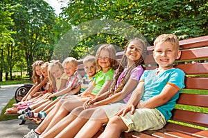 Happy children sit on the bench in park