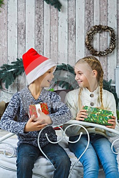 Happy children sitting on bed and holding gifts