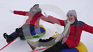 Happy children sledding in snow in the winter and waving their hands. family plays in winter park during the Christmas