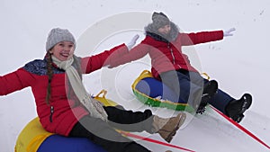 Happy children sledding in snow in the winter and waving their hands. family plays in winter park during the Christmas