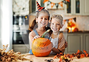 Happy children smiling with pumpkin during celebration, boy and girl preparing home Halloween decorations