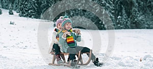 Happy children in snow. Two kids ride on a wooden retro sled on a winter day. Active winter outdoors games. Happy