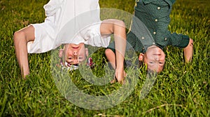 Happy children standing upside down on green grass