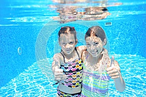 Happy children swim in pool underwater, girls swimming