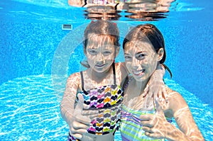 Happy children swim in pool underwater, girls swimming