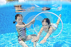 Happy children swim in pool underwater, girls swimming