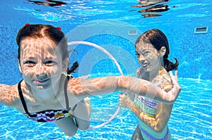 Happy children swim in pool underwater, girls swimming