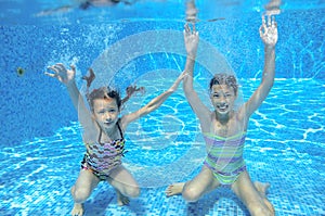 Happy children swim in pool underwater, girls swimming