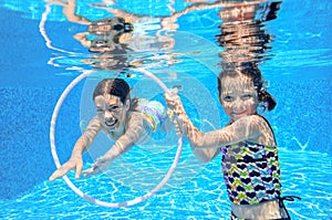 Happy children swim in pool underwater, girls swimming