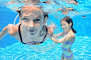 Happy children swim in pool underwater, girls swimming