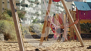 Happy children swinging outdoors. Boy and girl have fun on playground.