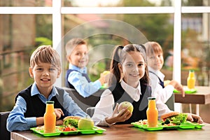 Happy children at table  healthy food in school canteen