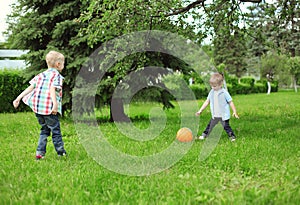 Happy children two boys together playing football with ball
