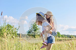 Happy children two girls sisters laughing and having fun in meadow