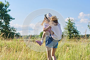 Happy children two girls sisters laughing and having fun in meadow