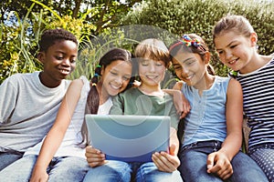 Happy children using digital tablet at park