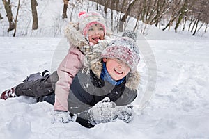 Happy children in winterwear laughing while playing in snowdrift outside. Winter childrens vacation