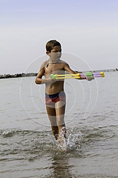 Happy childs play into sea with watergun, vacation in Italy