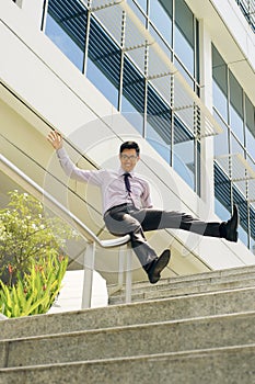 Happy Chinese Businessman Going Downstairs Sliding On Rail photo