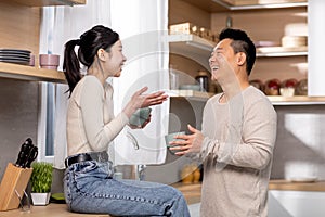 Happy chinese couple drinking coffee together at kitchen