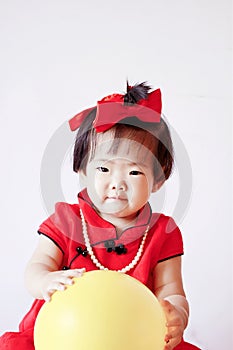 Happy Chinese little baby in red cheongsam play yellow balloon