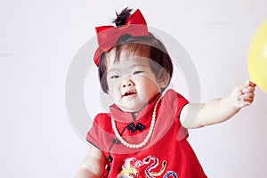 Happy Chinese little baby in red cheongsam play yellow balloon