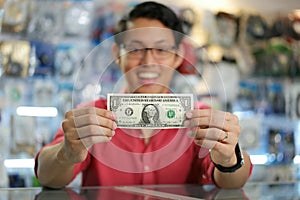 Šťastný čínština muž zobrazené prvý dolár zarábať v počítač obchod 