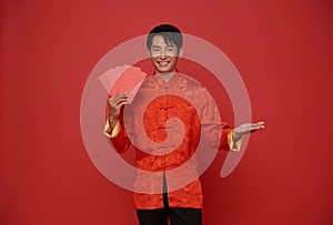 Happy Chinese new year 2024. Asian man wearing red traditional clothing holding angpao or red packet monetary gift
