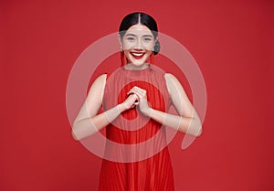 Happy Chinese new year. Asian woman wearing red dress with gesture of congratulation isolated on red copy space background