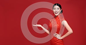 Happy Chinese new year. Asian woman wearing traditional cheongsam qipao dress with gesture of introduce isolated on red background