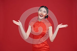 Happy Chinese new year. Asian woman wearing traditional cheongsam qipao dress with gesture of welcome isolated on red background