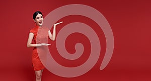 Happy Chinese new year. Asian woman wearing traditional cheongsam qipao dress with gesture of welcome isolated on red copy space