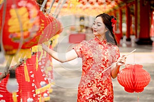 Happy Chinese new year. Asian woman wearing traditional cheongsam qipao dress looking confident holding and playing lantern while