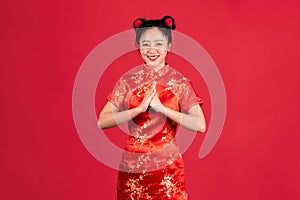 Happy Chinese new year. Beautiful Asian woman wearing red cheongsam qipao dress with gesture of congratulation isolated on red