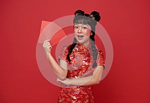 Happy Chinese new year. children asian girl wearing traditional cheongsam qipao dress holding red envelope or Ang Pao isolated on