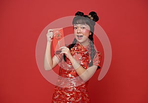Happy Chinese new year. Little asian girl wearing traditional cheongsam qipao dress holding red envelope with text means great