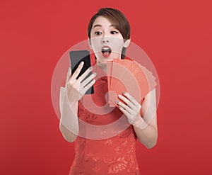 Happy chinese new year. suprised young Woman holding Red envelopes for lucky and watching the mobile phone