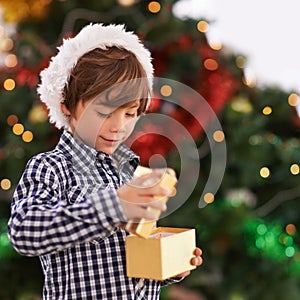 Happy, Christmas and boy child with gift for celebration or surprise at festive party at home. Smile, santa hat and cute