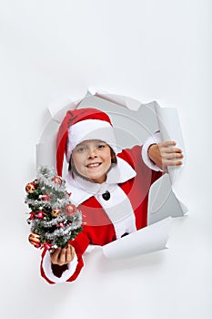 Happy christmas boy giving you a small decorated fir tree