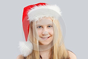 Happy Christmas child. Young girl in Santa hat laughing on gray background